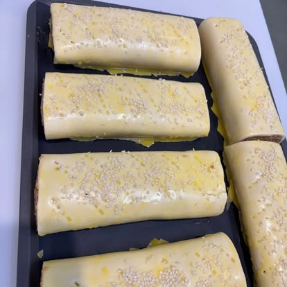 Fresh sausage rolls on a baking tray, ready for the oven